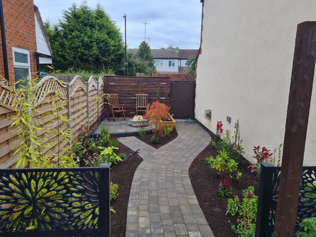 Curved garden path and planted borders beside a house